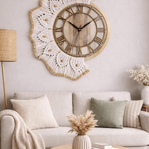 Puede incluir: Un gran reloj de pared redondo con una esfera de madera y números romanos. El reloj está rodeado por un diseño de macramé blanco con detalles dorados. El reloj está colgado sobre un sofá beige.