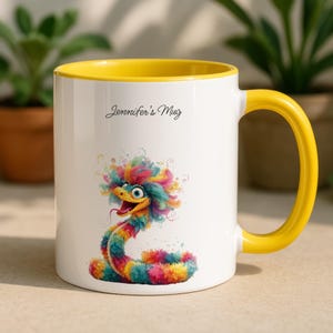 May include: White ceramic mug with a yellow interior and handle. The mug features a colourful illustration of a snake with a whimsical design. The text "Jennifer's Mug" is printed on the mug.