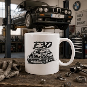 Könnte beinhalten: Ein weißer Keramikbecher mit einer schwarzen grafischen Illustration eines E30-Autos und dem darüber gedruckten Text E30. Der Becher verfügt über einen Standardhenkel und eine glatte Oberfläche, die ein detailliertes Automobildesign zeigt.