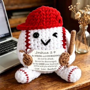Könnte beinhalten: Eine gehäkelte Baseball-Figur mit roter Mütze, die einen braunen Schläger hält und ein weißes Schild mit dem Text präsentiert: Joshua 1:9 Be STRONG and COURAGEOUS. Do not be afraid; Do not be discouraged, for the LORD your God God. will be with you wherever go. Live Love Baseball.