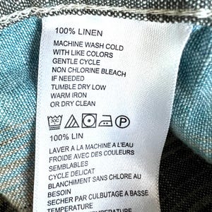 May include: A white fabric label with black text providing care instructions for a linen item. The label states "100% LINEN" and includes washing, drying, and ironing instructions, along with care symbols.