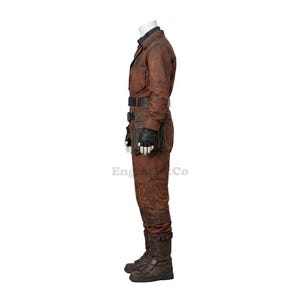 May include: Brown leather jumpsuit with a black belt, gloves, and boots. The outfit includes a utility belt with pouches and a collared shirt. The jumpsuit has a worn, distressed appearance, suggesting a vintage or rugged style.