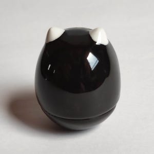 以下が含まれることがあります： 白耳のアクセントが付いた、光沢のある黒い猫型のボトルストッパー。 ストッパーは丸みを帯びた卵のような形で、ボトルにフィットするように設計されています。 デザインはシンプルでエレガントです。