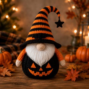 Peut inclure: Une figurine de gnome au crochet avec un grand chapeau pointu à rayures horizontales orange et noires, surmonté d'une petite étoile noire. Le gnome possède une barbe en fausse fourrure blanche, un nez beige rond et un corps en forme de citrouille noire avec un visage de lanterne orange.