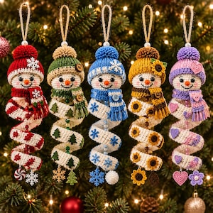 May include: Five hanging crochet snowman ornaments with spiral bodies. Each snowman wears a knit hat and scarf with unique accents: red with snowflakes, green with trees, blue with snowflakes, yellow with sunflowers, and purple with hearts.