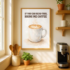 Może przedstawiać: Oprawiony wydruk z napisem "IF YOU CAN READ THIS, BRING ME COFFEE" nad akwarelowym obrazem filiżanki kawy z wzorem w kształcie serca w pianie. Wydruk jest w drewnianej ramie.