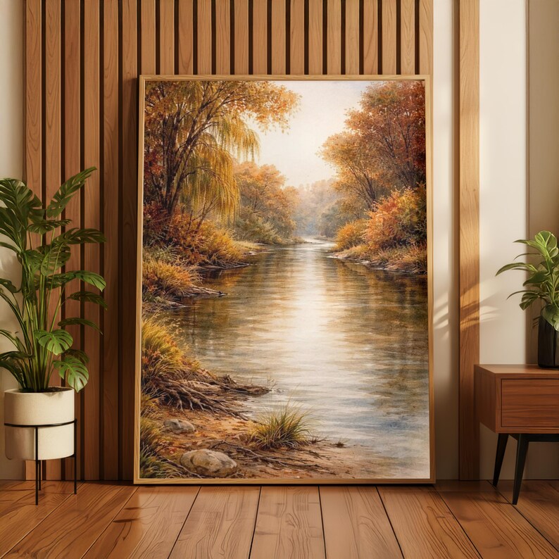 May include: A framed landscape painting depicts a serene river scene. The artwork features a river flowing through a forest with trees in autumn colors. The painting is in a wooden frame and is displayed indoors.