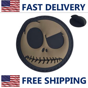 May include: A round patch featuring a stylized skull face with a stitched mouth and large eye sockets. The face is tan with black eye and mouth details, set against a black background. The words "FAST DELIVERY" and "FREE SHIPPING" are displayed.