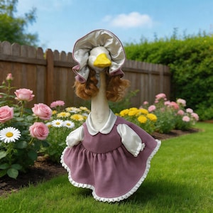 Puede incluir: Una caprichosa figura de ganso vestida con un vestido malva con ribetes y mangas blancas, un gorro a juego y una peluca rizada color castaño rojizo. El ganso tiene un pico amarillo y posa en un jardín con rosas rosas y margaritas.