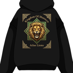 Peut inclure: Un sweat-shirt à capuche noir avec un motif au dos. Le design présente une tête de lion dorée centrée dans une étoile géométrique verte et dorée. Le texte Kingdom Of Morocco figure au-dessus du lion, et Atlas Lions en dessous.