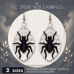 Op de afbeelding: Een paar wit-zwarte FSL SPIDER WEB EARRINGS met een druppelvormig wit geborduurd web en een zwarte spin in het midden. De oorbellen hangen aan zilverkleurige metalen haakjes. De tekst luidt FSL SPIDER WEB EARRINGS.