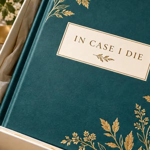 May include: A dark teal hardcover book with gold foil leaf illustrations on the cover. A central rectangular label features the text "IN CASE I DIE" in black lettering, accented by a small gold leaf graphic below the words.