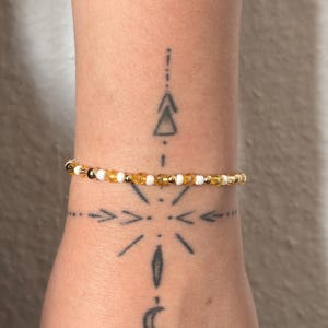 Peut inclure: Un bracelet de perles délicat composé d'un motif répétitif de petites perles facettées translucides couleur ambre, de perles rondes blanc opaque et de minuscules perles intercalaires métalliques dorées disposées en un seul rang.