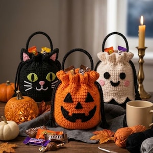 May include: Three crocheted drawstring bags for Halloween. One is a black cat with green eyes, one is an orange jack-o'-lantern with a black face, and one is a white ghost with black eyes and pink cheeks. Each bag has a black handle and contains candy.