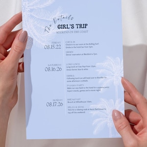 May include: A light blue rectangular itinerary card featuring white palm tree illustrations and black text. The header reads The Details GIRL'S TRIP WEEKEND ON THE COAST, followed by a schedule for Friday, Saturday, and Sunday with specific event details.