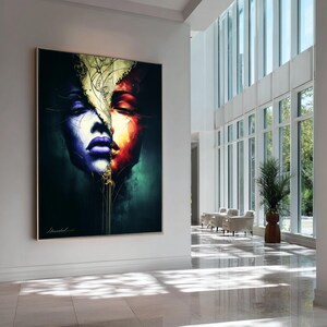 May include: Large framed artwork featuring a split face portrait. One side is blue and purple, the other red and orange. A gold leaf design separates the two sides. The artwork is displayed in a bright, modern hallway.