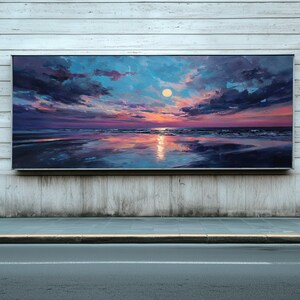 Puede incluir: Una gran pintura rectangular representa una puesta de sol sobre una playa. El cielo transita del azul al rosa y al morado, con nubes oscuras. El sol es un globo amarillo brillante. El agua refleja los colores del cielo, creando un paisaje sereno y colorido.