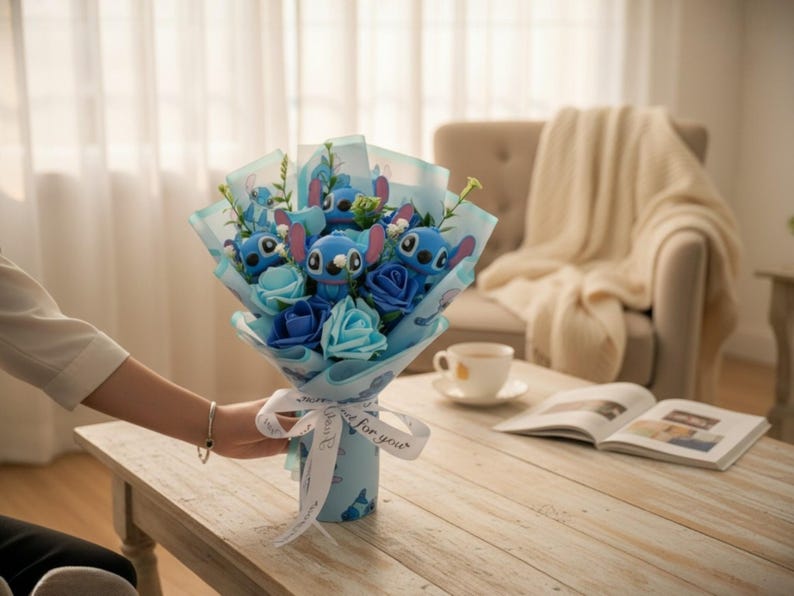 May include: A bouquet featuring blue plush Stitch characters and blue fabric flowers. The bouquet is wrapped in light blue paper and tied with a white ribbon that says "for you". The bouquet is on a wooden table.