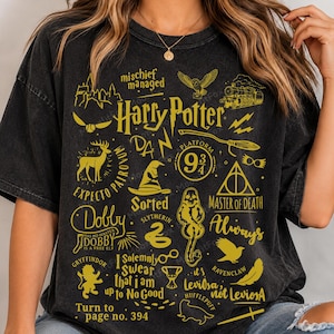 May include: A black short-sleeve t-shirt featuring a yellow graphic print with various Harry Potter themed icons and text including Mischief Managed, Platform 9 3/4, Expecto Patronum, Dobby, Master of Death, Always, and Turn to page no. 394.