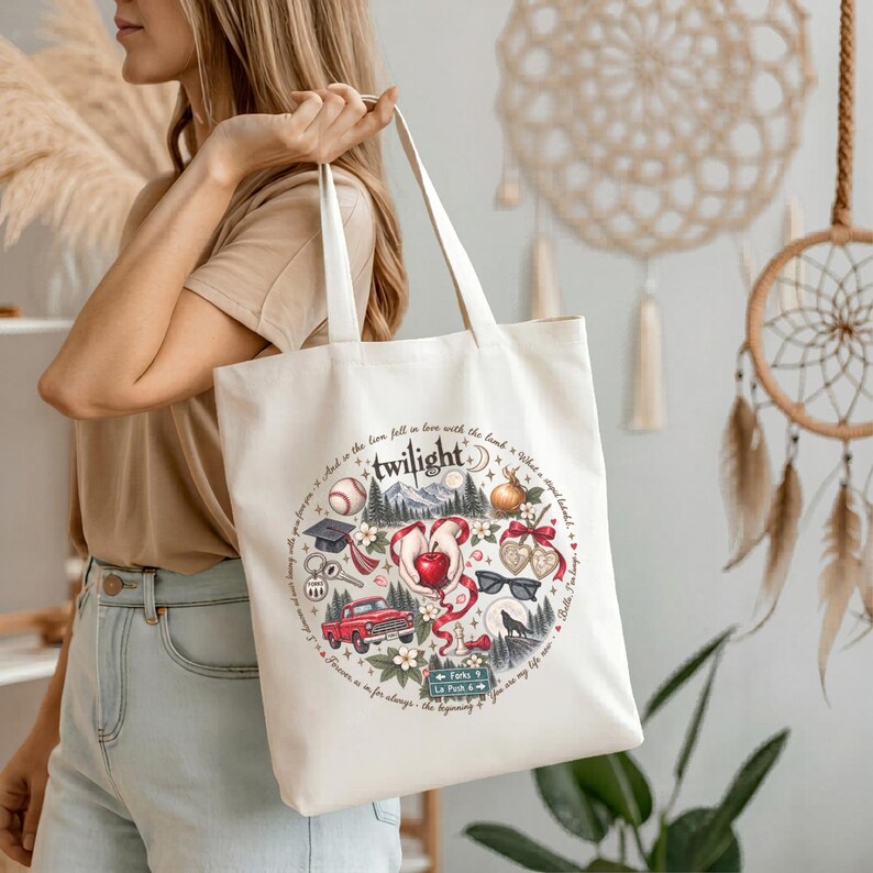May include: A cream-colored canvas tote bag featuring a circular graphic print with the word Twilight at the top. The design includes illustrations of a red apple, a red truck, a graduation cap, a baseball, sunglasses, and a road sign reading Forks.