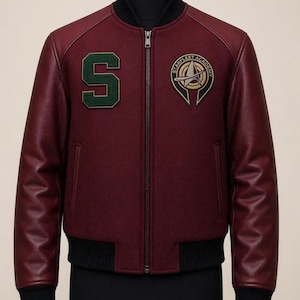 Pode incluir: Casaco bomber bordô com gola, punhos e bainha canelados pretos. Apresenta mangas de couro bordô, fecho de correr e dois patches: um "S" verde e o emblema da Starfleet Academy.