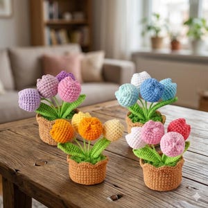Peut inclure: Quatre arrangements de fleurs de tulipes au crochet dans de petits pots bruns. Les tulipes sont de différentes couleurs, dont le rose, le violet, l'orange, le jaune, le bleu et le blanc. Les fleurs ont des tiges et des feuilles vertes. Les pots sont sur une table en bois.