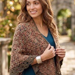 May include: A brown and green crochet shawl with a scalloped edge. The shawl is draped over the shoulders. The woman is wearing a silver bracelet and a teal top.