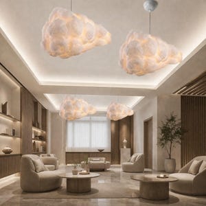 May include: Cloud-shaped pendant lights illuminate a modern living room. The lights are white and textured, resembling fluffy clouds. The room features neutral-toned furniture, wooden accents, and a minimalist design, creating a serene atmosphere.