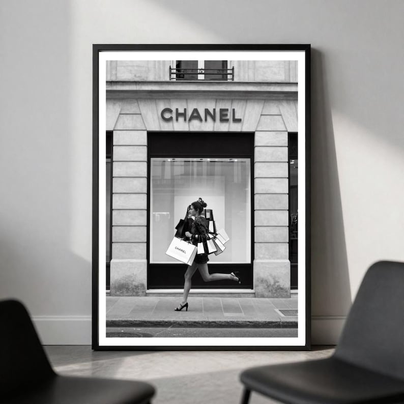 Puede incluir: Impresi&oacute;n en blanco y negro enmarcada que muestra a una persona corriendo con bolsas de compras frente a una tienda Chanel. El nombre de la tienda es visible sobre la entrada. Una imagen elegante que captura la esencia del lujo y la moda.