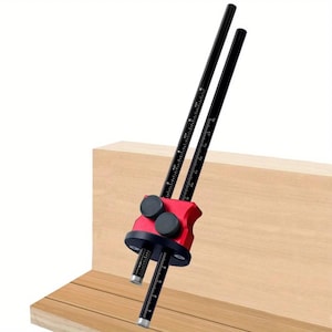 Puede incluir: Un calibrador de marcado rojo y negro para carpintería, con dos varillas negras con escalas de medición. La herramienta se coloca contra una superficie de madera marrón claro, ideal para trabajos de carpintería. Las varillas tienen medidas métricas.
