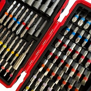 Pode incluir: Um conjunto de várias pontas de chave de fenda e soquetes, cuidadosamente organizado em uma caixa de plástico vermelha e preta. As pontas têm hastes prateadas com faixas coloridas, incluindo laranja, azul, vermelho e amarelo. A caixa está aberta, revelando vários compartimentos.