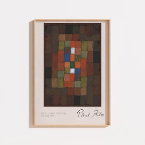 Pode incluir: Uma impressão de arte emoldurada apresentando uma grade de blocos retangulares em tons de marrom, verde, laranja, azul e branco. O texto diz Static-Dynamic Gradation Paul Klee 1923. A obra está dentro de uma moldura de madeira clara.