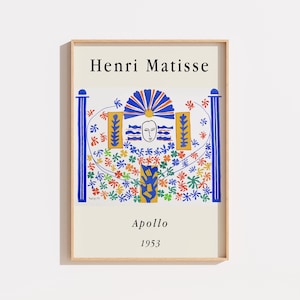 Peut inclure: Une impression d'art encadrée intitulée Henri Matisse Apollo 1953. L'image présente un visage central entouré de formes florales abstraites bleues, orange, vertes et rouges, flanqué de deux piliers bleus sur un fond crème dans un cadre en bois clair.