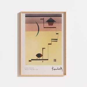 Peut inclure: Une impression d'art encadrée représentant l'œuvre Eding de Wassily Kandinsky de 1938. La composition abstraite présente un fond jaune avec des lignes géométriques, un croissant sombre, une forme triangulaire et une signature en bas à droite.