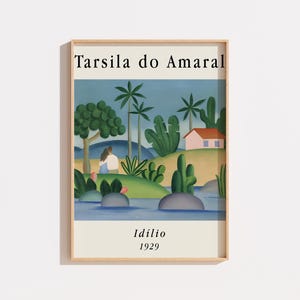 May include: A framed art print featuring Tarsila do Amaral's painting Idílio 1929. The artwork depicts a landscape with a small house, palm trees, and two figures sitting by a blue river. The print is set within a light wood frame on a white background.