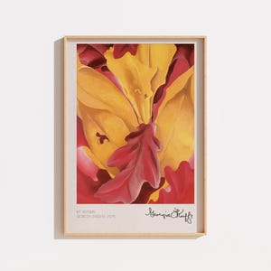 Peut inclure: Une impression d'art encadrée représentant une peinture en gros plan de feuilles d'automne aux teintes vives de jaune, orange et rouge profond. La marge inférieure inclut le texte MY AUTUMN, GEORGIA O'KEEFFE 1929 et la signature de l'artiste.