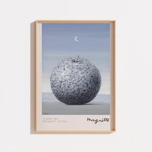 Peut inclure: Une impression d'art encadrée représentant une grande pomme grise texturée centrée sur un ciel bleu sourd avec un fin croissant de lune. La marge inférieure affiche le texte LA GRANDE TABLE, RENE MAGRITTE (1962-1963) et la signature Magritte.