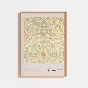 Peut inclure: Une affiche murale rectangulaire encadrée présentant un motif floral répétitif dans des tons crème, jaune pâle et orange doux. La marge inférieure comprend le texte Leicester William Morris 1870 et la signature William Morris.