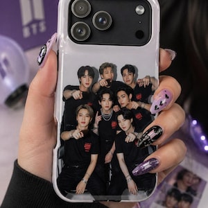 Könnte beinhalten: Weißes Handycase mit einer Gruppe von sieben Personen in schwarzen Hemden. Das Case hat ein lila BTS-Logo und die Worte "I Purple You". Das Handycase wird in einer Hand mit lila und schwarzer Nagelkunst gehalten.