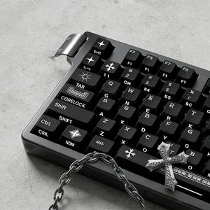 May include: A black mechanical keyboard with white lettering and symbols. A silver chain and a decorative silver cross are in the foreground. The keyboard has a unique design with custom keycaps.