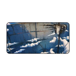 May include: A rectangular desk mat featuring a detailed illustration of a massive, weathered industrial structure suspended in a blue sky with white clouds. The structure displays dark metallic textures and Japanese characters on its side.