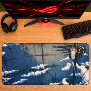 May include: A rectangular desk mat featuring a detailed science fiction illustration of a massive, towering structure rising above clouds, with a complex mechanical station displaying Japanese characters on its side, set against a deep blue sky.