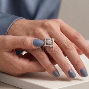 Bridal jewelry photo displaying a geometric square halo ring option on plain white background fabric. This 14k gold engagement ring piece boasts incredible sparkle symmetry from the layered open facets. An ideal wedding band style alternative that offers sustainable eco luxury appeal for modern brides. This personalized snowflake shape details deliver vintage aesthetics straight into your online shop.