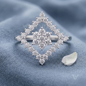Front view studio shot of an art deco style ring featuring a custom 14k gold frame. The main stone shape is a geometric square halo holding an elegant lab diamond snowflake cluster. Crafted for modern brides seeking bespoke fine jewelry with a luxury look. Perfect sustainable diamond statement piece option for a unique wedding band look, showing incredible symmetry and craftsmanship in white tone.