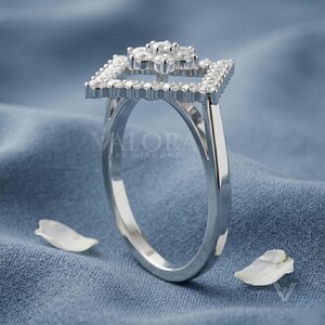 Angled studio shot displaying a brilliant moissanite stone piece crafted in 925 sterling silver band. Showcasing fire sparkle and D color VVS1 clarity stones embedded within the open tiered flower halo. This handmade design offers affordable luxury styling for women seeking a unique personalized gifts. An exquisite travel safe ring concept that provides maximum brilliance under any formal light beam.