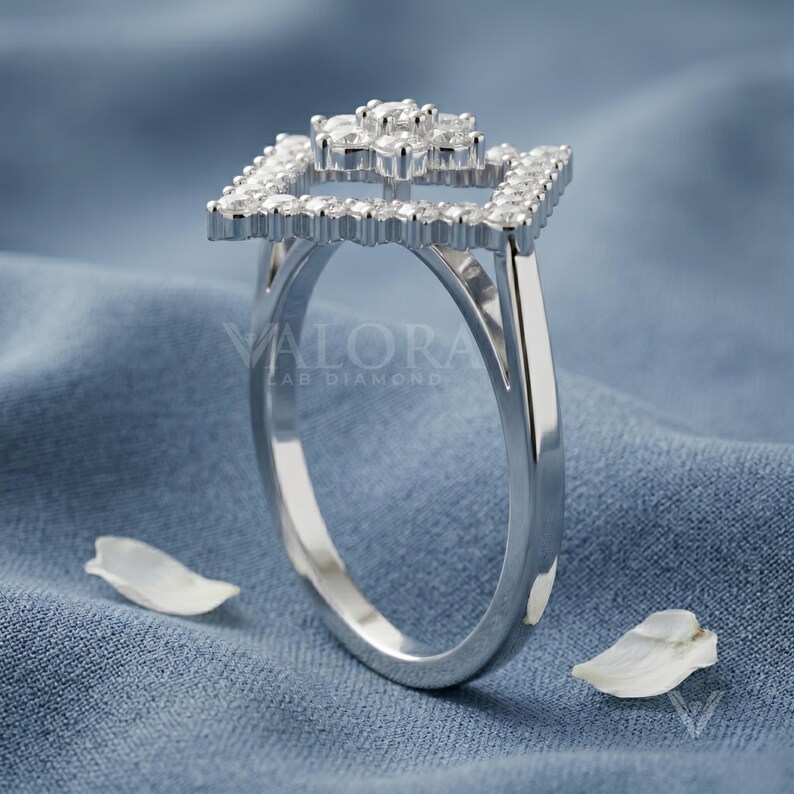 Angled studio shot displaying a brilliant moissanite stone piece crafted in 925 sterling silver band. Showcasing fire sparkle and D color VVS1 clarity stones embedded within the open tiered flower halo. This handmade design offers affordable luxury styling for women seeking a unique personalized gifts. An exquisite travel safe ring concept that provides maximum brilliance under any formal light beam.