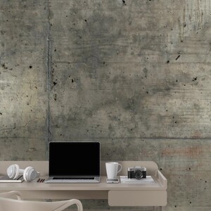 Peut inclure: Un bureau aux tons neutres avec un ordinateur portable, un casque, une tasse, un smartphone et un appareil photo vintage. Le bureau est plac&eacute; contre un mur en b&eacute;ton textur&eacute;. Une chaise blanche est devant le bureau.