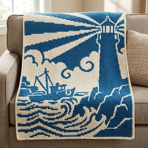 May include: A rectangular crochet blanket featuring a two-tone blue and cream design. The pattern depicts a lighthouse on a rocky shore with a fishing boat on the water. Beams of light radiate from the lighthouse tower across the upper section.