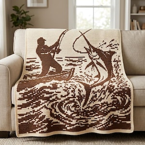 May include: A rectangular crochet blanket featuring a two-tone brown and cream design. The pattern depicts a silhouette of a person in a small boat fishing with a rod, while a large marlin leaps out of the water, creating a detailed graphic scene.