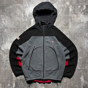 May include: A black, gray, and red Polo Sport hooded jacket. The jacket has a full zipper, a hood, and the Polo Sport logo on the chest. The sleeves have a red accent and a small American flag patch.